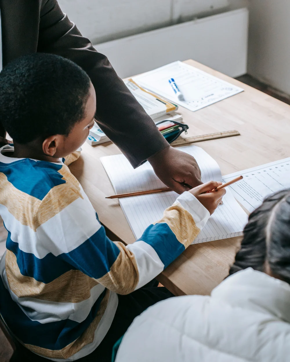 Teacher supporting a learner with written classroom work